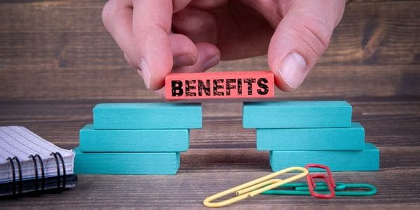 Benefits written on a red coloured wooden block stacked on top of some blue blocks.