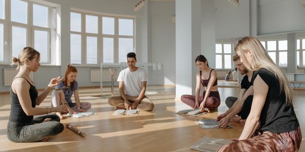 A group of people in a large hall practicing group meditation.