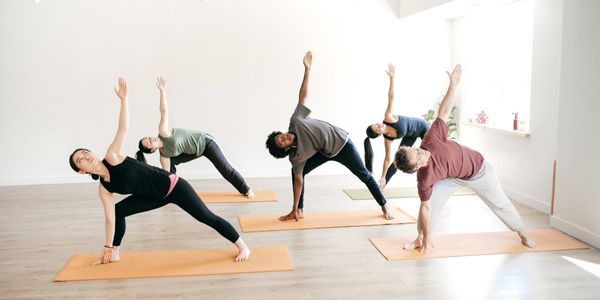 A yoga class in session performing exercises with hands in the air.
