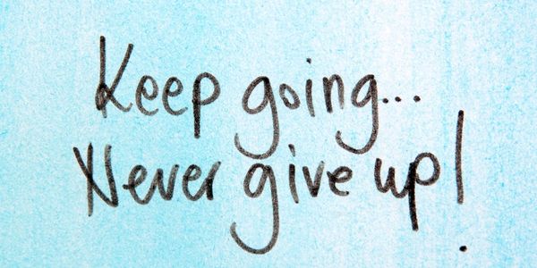 Keep going... Never give up hand written on blue background.