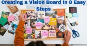 woman creating inspiring vision board on a desk surrounded with materials with bold blue text that reads; Creating A Vision Board In 8 Easy Steps